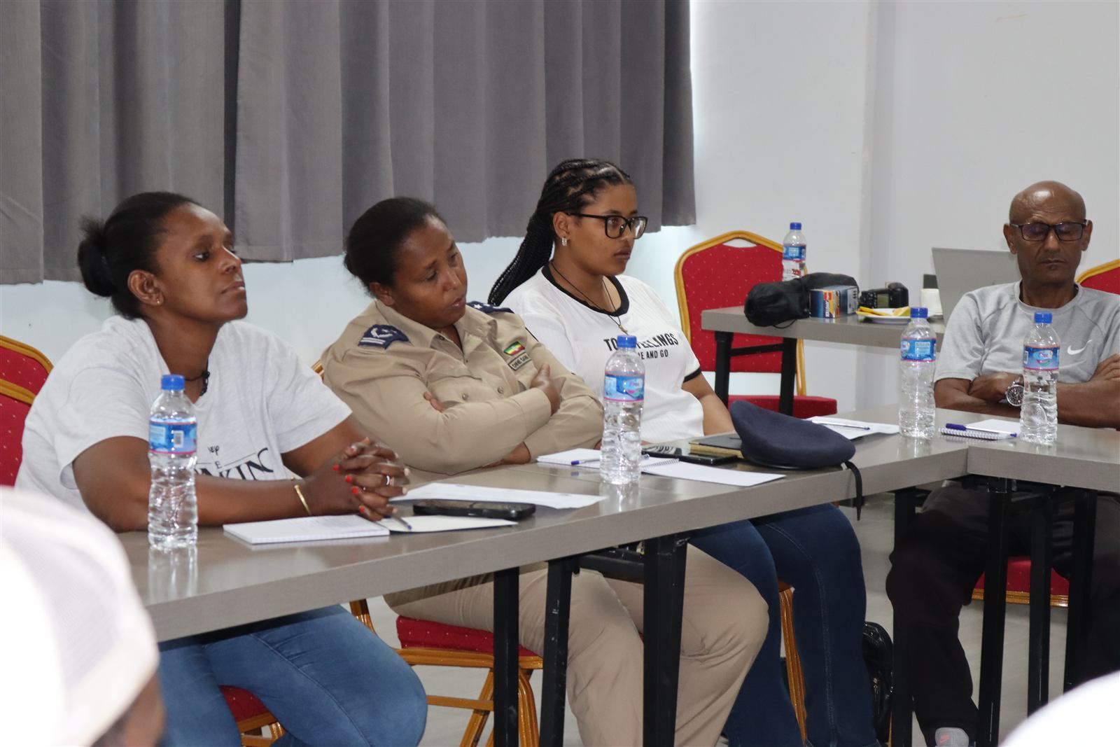 A uniformed government official seated at the table alongside community participants