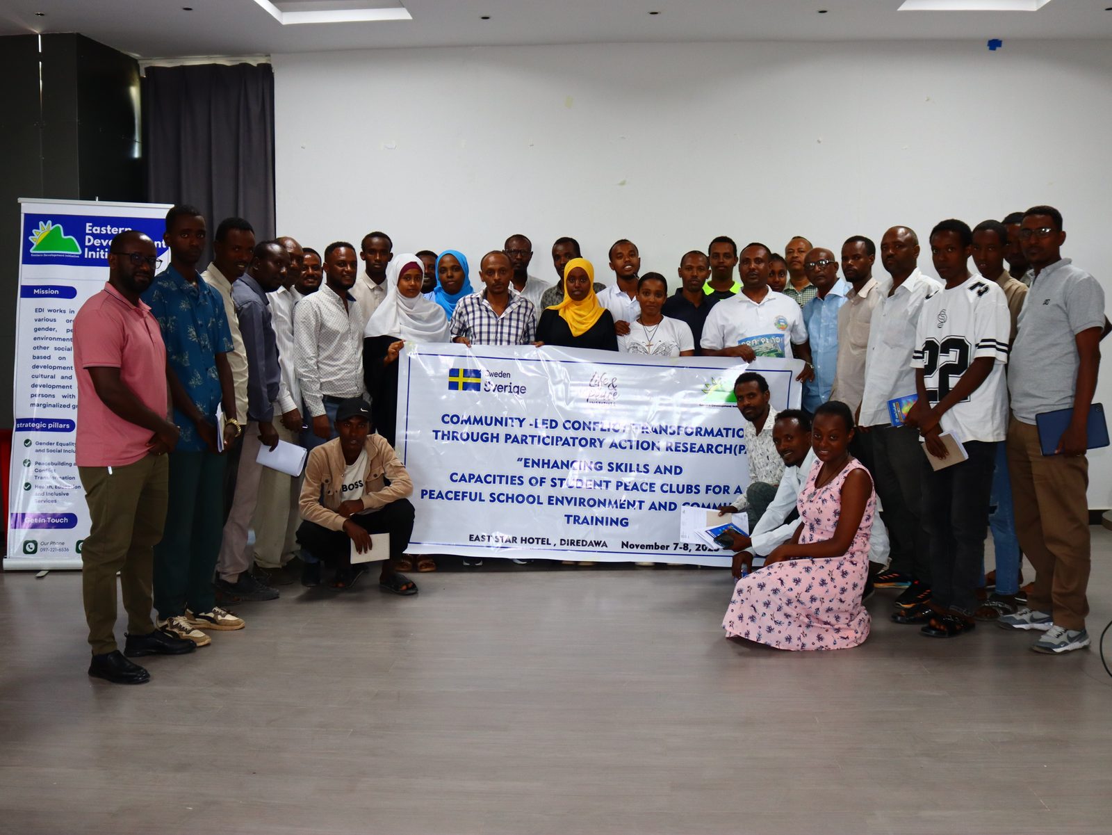 Full closing group photo of about thirty participants holding the training banner, venue and date fully legible