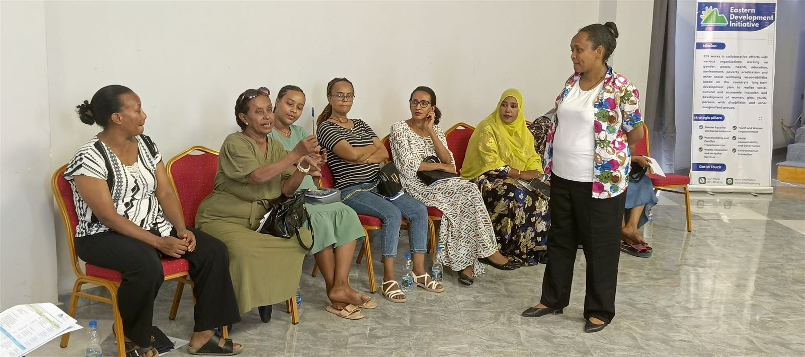 Small group of seven women in conversation with a standing facilitator
